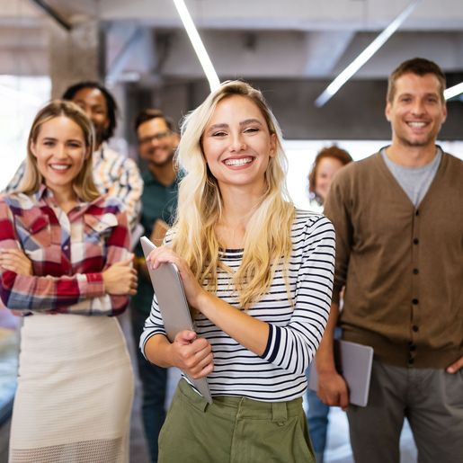 Gruppe mit lächelnden Erwachsenen in lässiger Kleidung, die in einem modernen Büro stehen